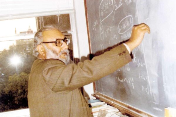 Salam lecturing at Imperial, 1986 Abdus Salam writing on a blackboard. The equations include a parity and angular momentum operators. It's not the most flattering picture, as Salam seems to be mid-blink.