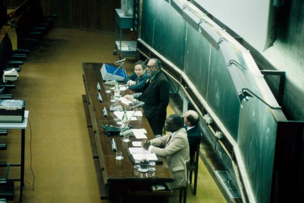 ICTP workshop, 1985 Abdus Salam speaking at a workshop. He stands in front of an auditorium of people, speaking into a microphone.