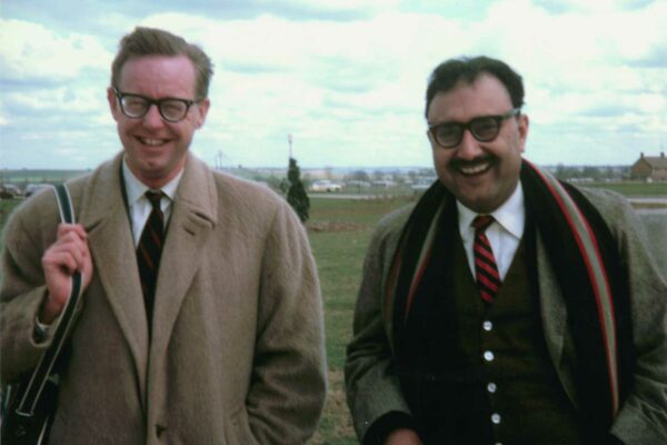 Ward and Salam, 1964 Abdus Salam standing with John C. Ward in a grassy green field. They are dressed in coats, and are laughing.