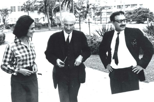 Oppenheimer with Salam, 1965 Abdus Salam standing with J.R. Oppenheimer and Sevda Arif. Everyone is smiling as they are engaged in conversation.